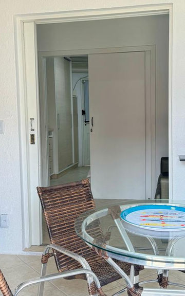 Cozinha do Apartamento 07 com lavadora, mesa e cadeiras.