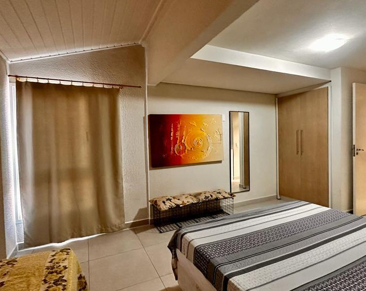 Quarto moderno com cama de casal, quadro vibrante e escada.
