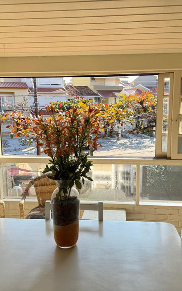 Mesa de jantar com vaso de flores em varanda envidraçada.