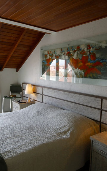 Quarto do Apartamento 29 com teto de madeira e luminárias.