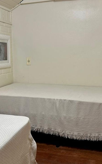 Quarto com duas camas de solteiro e cômoda de madeira no Apartamento 34.