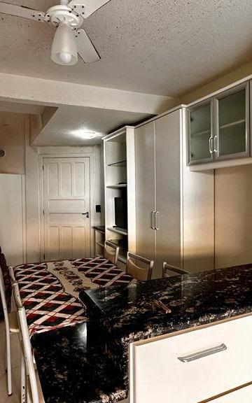Cozinha integrada com bancada, armários e escada ao fundo.