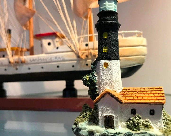 Miniatura de farol P&B e barco de madeira no Apartamento 51