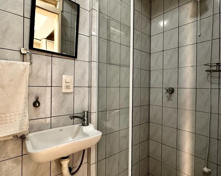 Banheiro do Apartamento 23 com pia branca e box de vidro