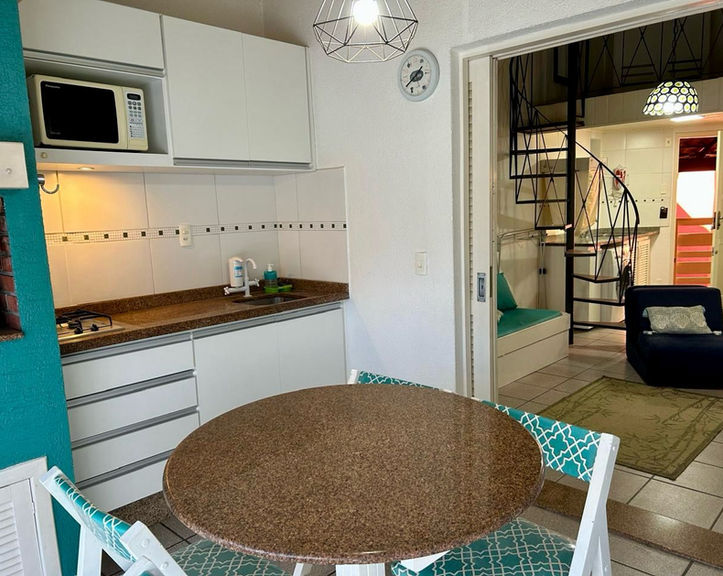 Cozinha integrada com mesa redonda e vista para escada caracol no Apartamento 47