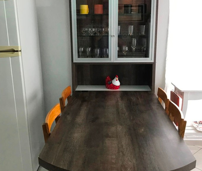 Mesa de madeira com cadeiras e cristaleira ao fundo no Apartamento 50