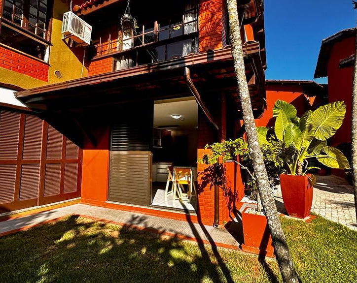 Área externa do Apartamento 06 com gramado e plantas.