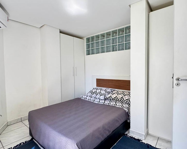 Quarto do Apartamento 54 com cama de casal e armários brancos.