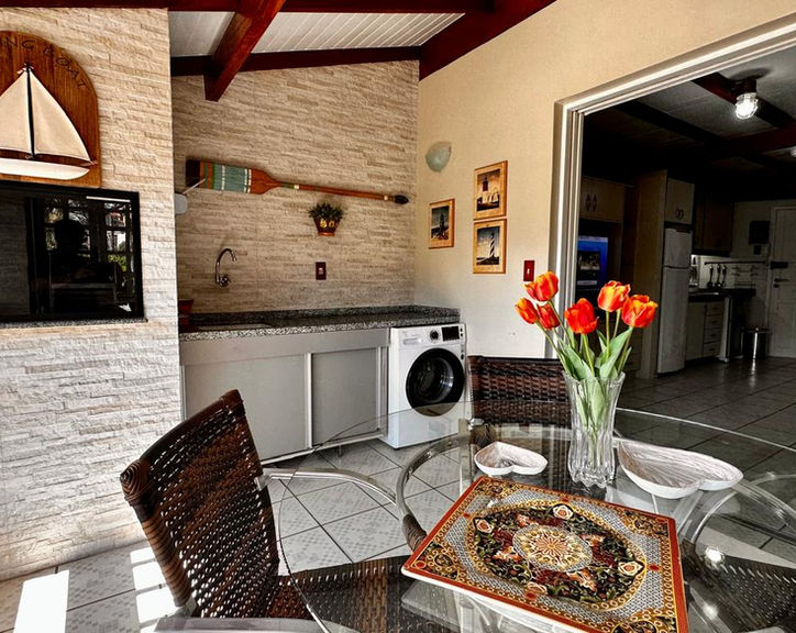 Varanda gourmet do Apartamento 35 com mesa e churrasqueira.