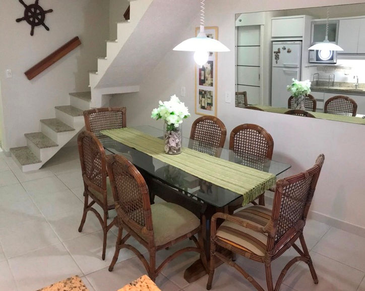Sala de jantar com mesa de vidro e cadeiras de vime