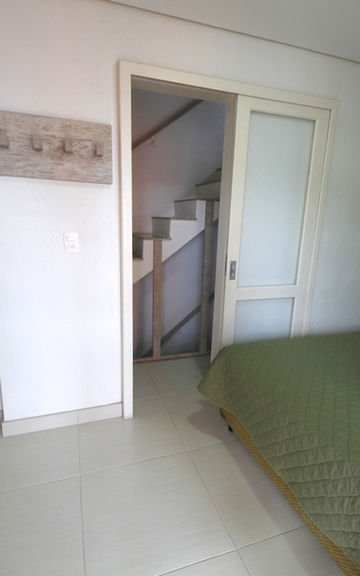 Quarto com cama verde, vista para o banheiro e escada.