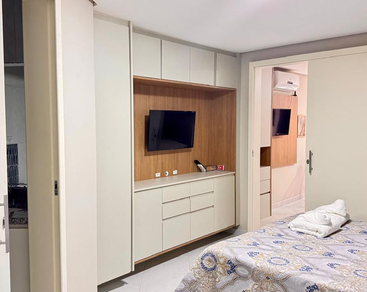 Quarto com móveis planejados, cama e TV no Apartamento 53