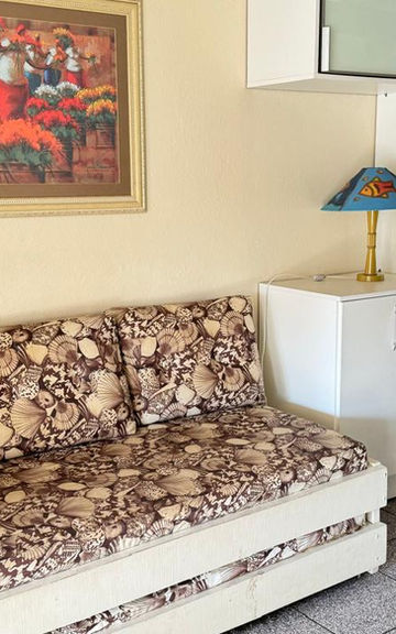 Sala do Apartamento 34 com sofá estampado e geladeira.