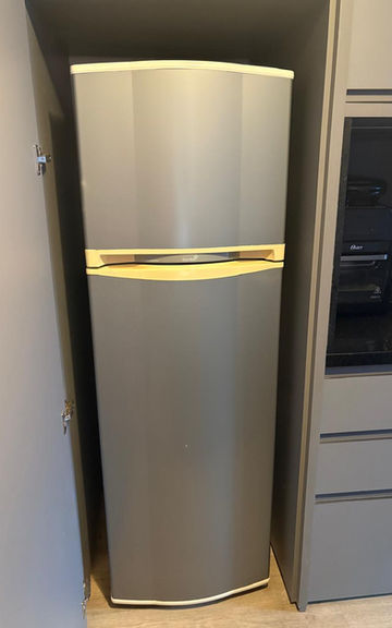 Geladeira duplex prata embutida em armário planejado cinza.