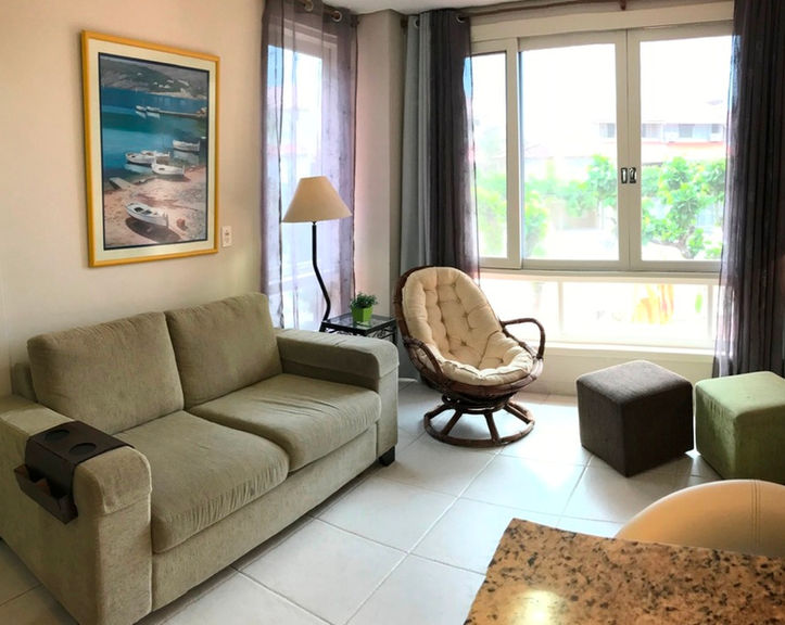 Sala do Apartamento 51 com sofá, poltrona e janela ampla.