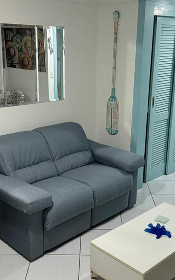 Sala de estar com sofá azul, poltrona e porta azul clara.