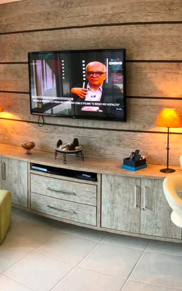 Sala do Apartamento 51 com painel de madeira e TV ligada.