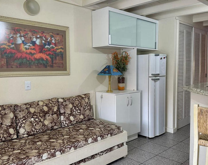 Sala do Apartamento 34 com sofá estampado e cozinha compacta.