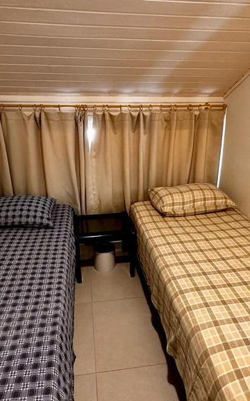 Quarto com duas camas de solteiro e teto inclinado.