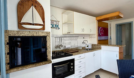 Cozinha integrada com 1 dormitório, armários brancos e decoração náutica.