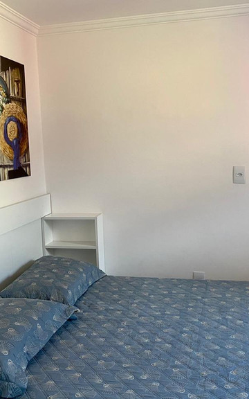 Quarto do Apartamento 33 com cama de casal e quadro de chapéus.