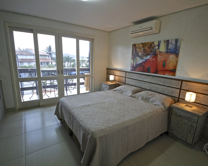 Quarto de casal do Apartamento 29 com varanda e quadro colorido.