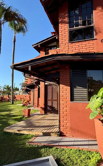 Fachada de tijolos do Apartamento 32 com palmeiras e jardim.