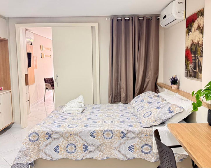 Quarto decorado do Apartamento 53 com cama de casal e mesa de trabalho.