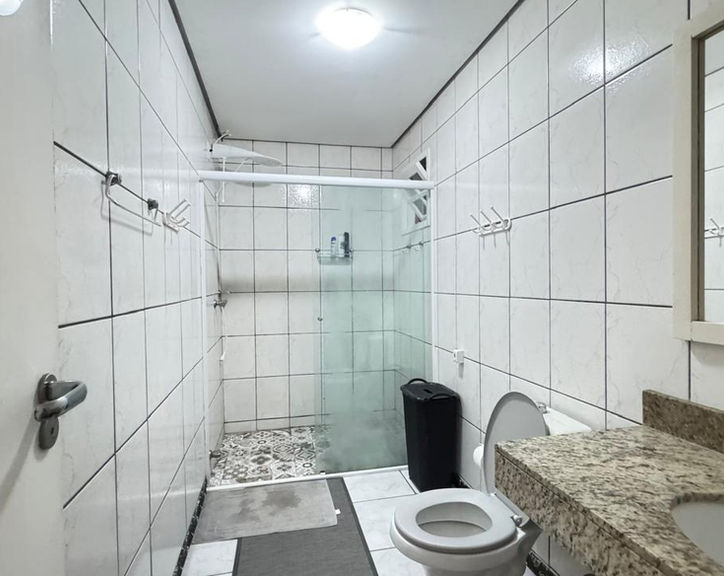 Banheiro do Apartamento 54 com box de vidro e bancada.