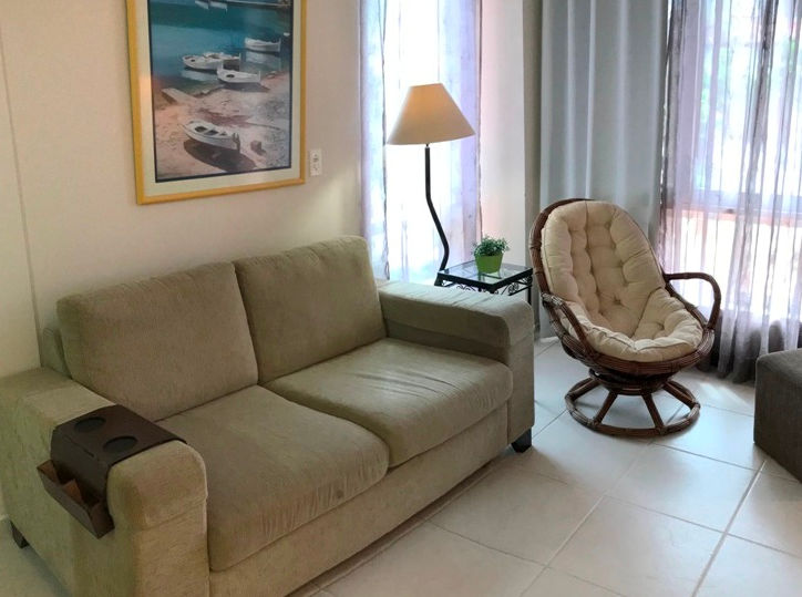 Sala de estar com sofá bege e poltrona redonda giratória.