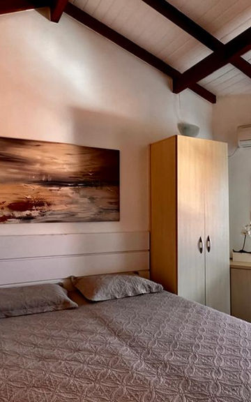 Quarto do Apartamento 35 com cama de casal e teto de madeira.