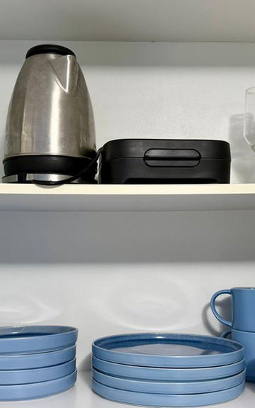 Armário de cozinha com louças azuis e cafeteira elétrica.