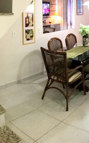 Sala de jantar com mesa e cadeiras de palha ao lado da escada