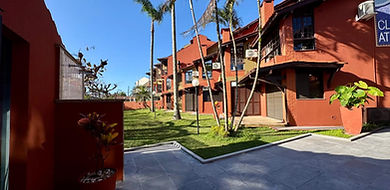 Fachada do Apartamento 33 com jardim e palmeiras.