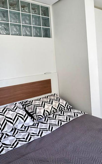 Quarto moderno com cama de casal e tijolos de vidro.