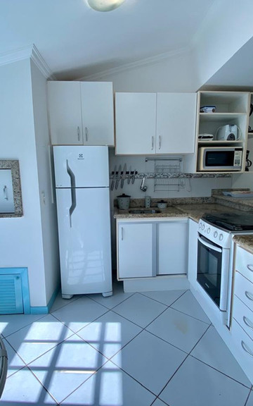 Cozinha integrada do Apartamento 33 com armários brancos.