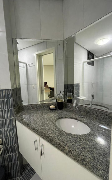 Banheiro do Apartamento 53 com bancada de granito e espelho.