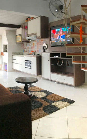 Sala do Apartamento 50 com sofá, escada caracol e cozinha.