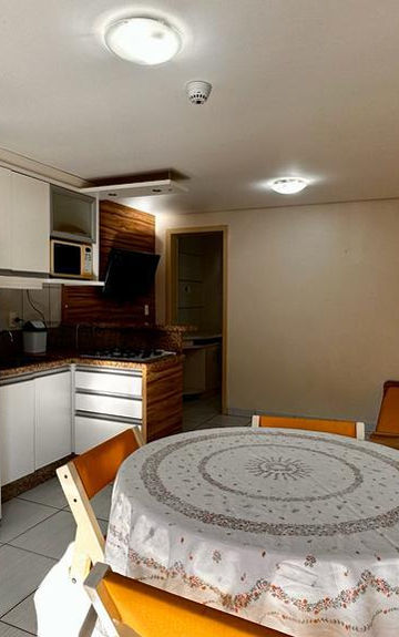 Cozinha integrada com sala, geladeira branca e mesa redonda