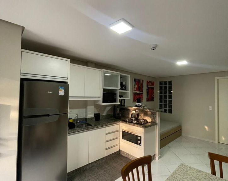 Cozinha moderna do Apartamento 53 com geladeira e armários.