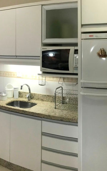 Cozinha planejada com armários brancos e eletrodomésticos.