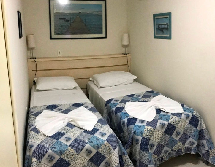 Quarto com duas camas de solteiro e colchas azuis.