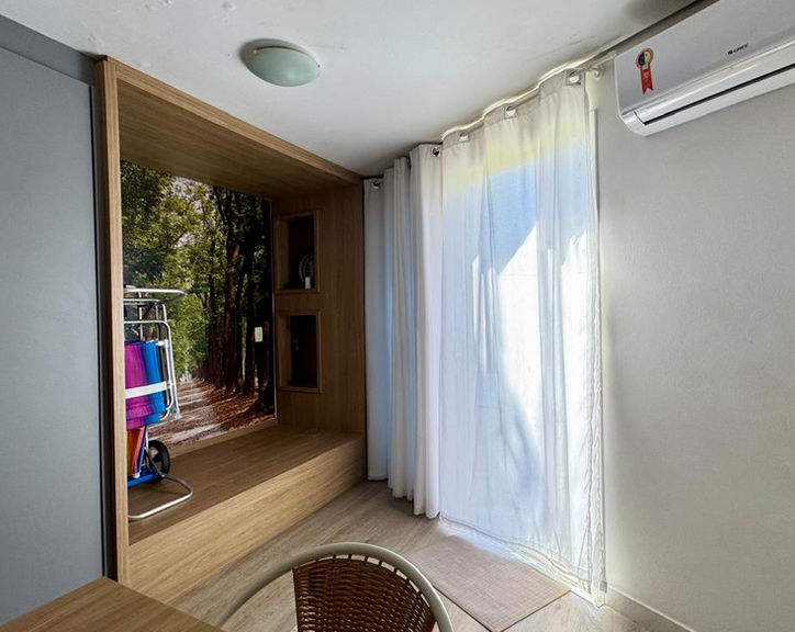 Quarto iluminado do Apartamento 54 com ar-condicionado e cortina branca.