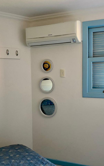 Quarto do Apartamento 33 com ar-condicionado e janela azul.