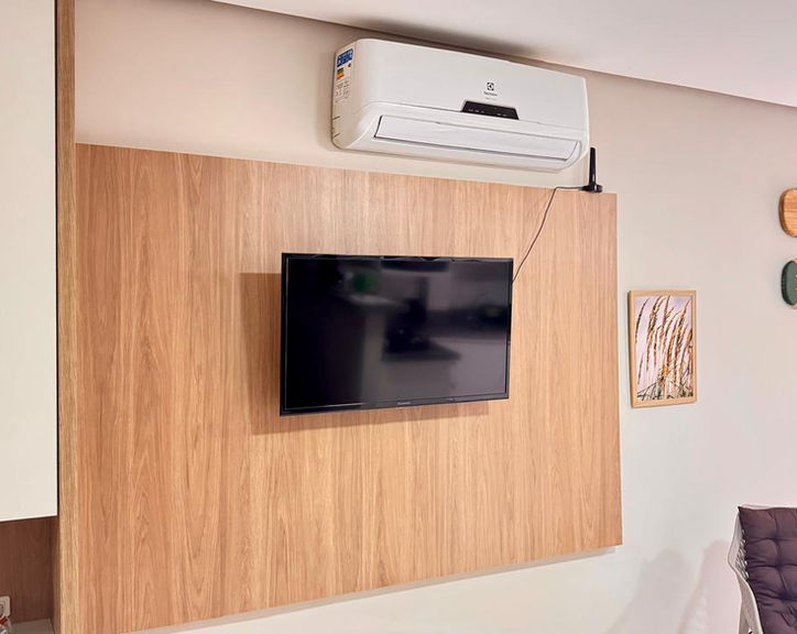 Painel de TV em madeira com ar-condicionado e decoração.