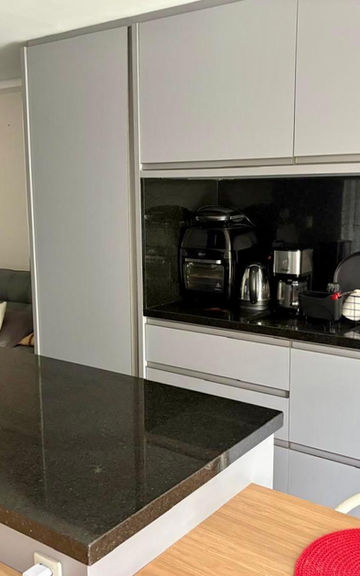 Cozinha planejada cinza com bancada preta no Apartamento 54
