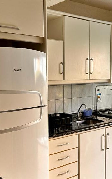 Cozinha planejada com geladeira branca e fogão no Apartamento 23