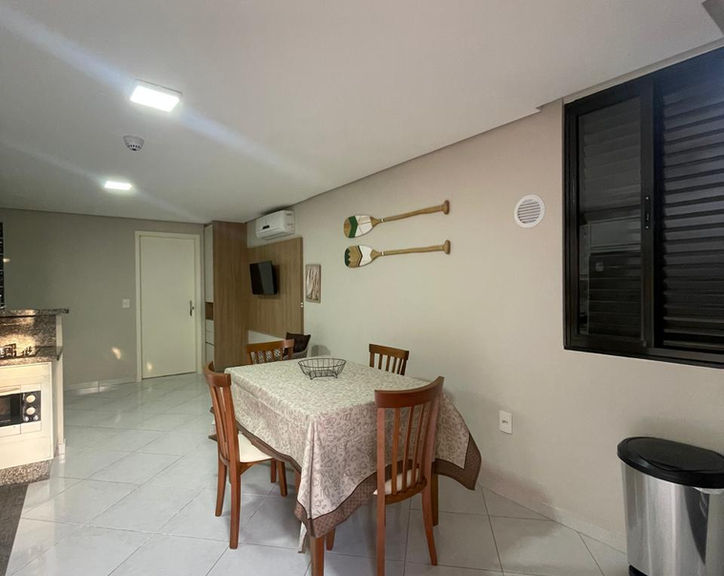 Sala de jantar com mesa, quatro cadeiras e decoração na parede.
