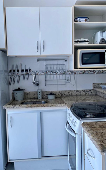 Cozinha planejada branca com micro-ondas e geladeira.