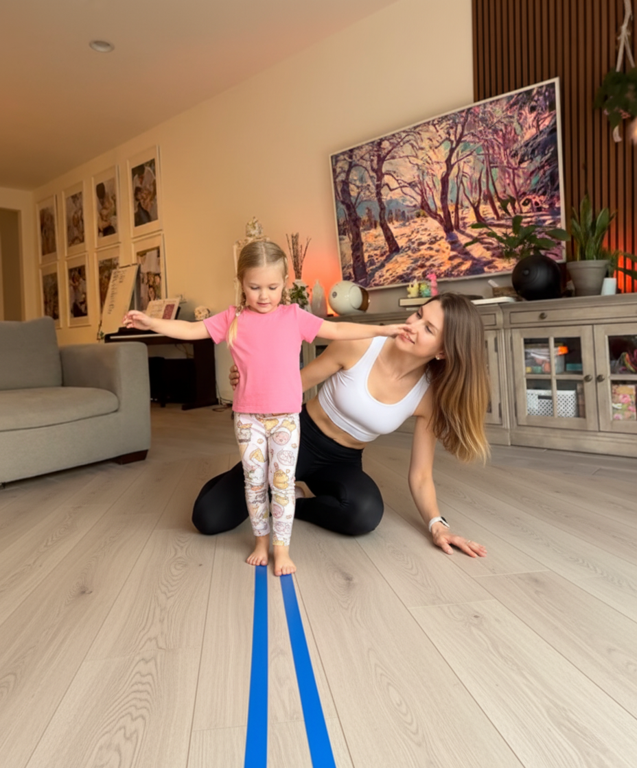 Mom helping her preschooler walk heel-to-toe along a tape line on the living room floor